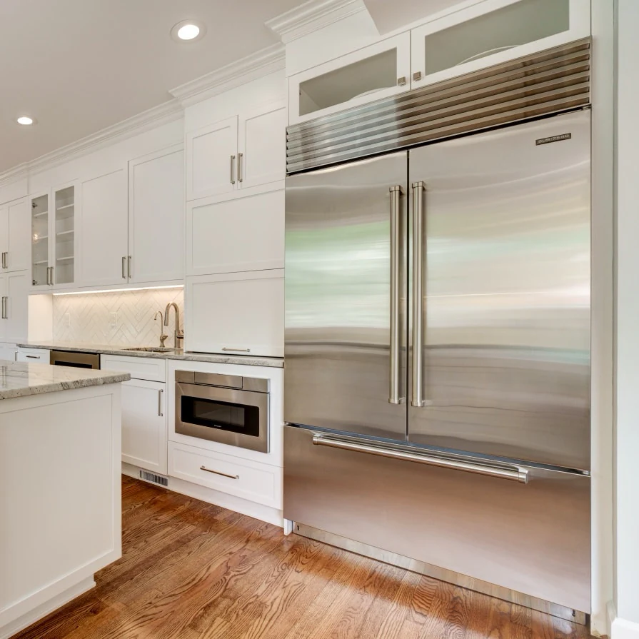 Stainless built-in French-door refrigerator set into white cabinets, with a drawer microwave beside it